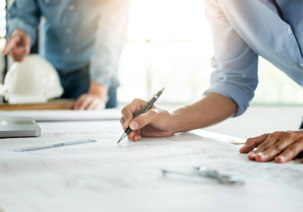 Close-up Of Person's engineer Hand Drawing Plan On Blue Print with architect equipment, Architects discussing at the table, team work and work flow construction concept.