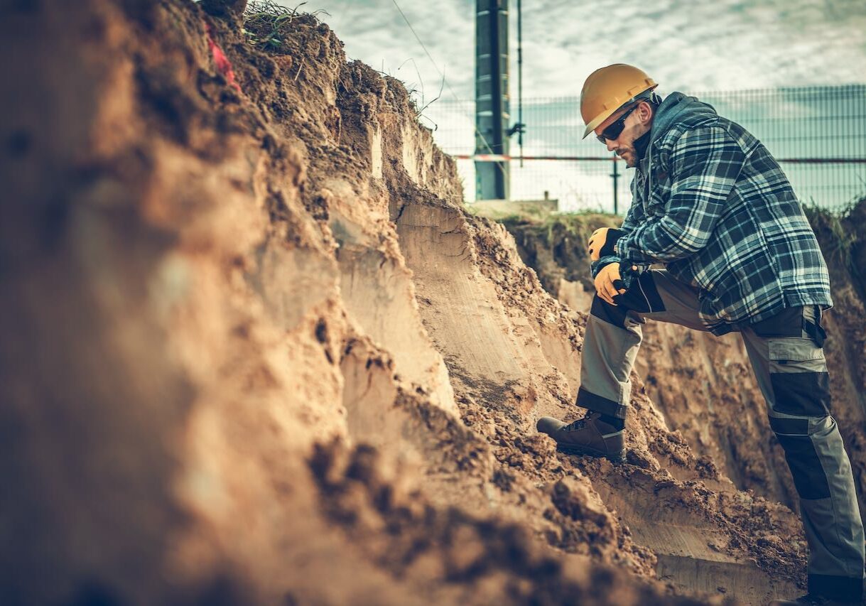 Caucasian Construction Worker Checking on a Soil Within Building Area.