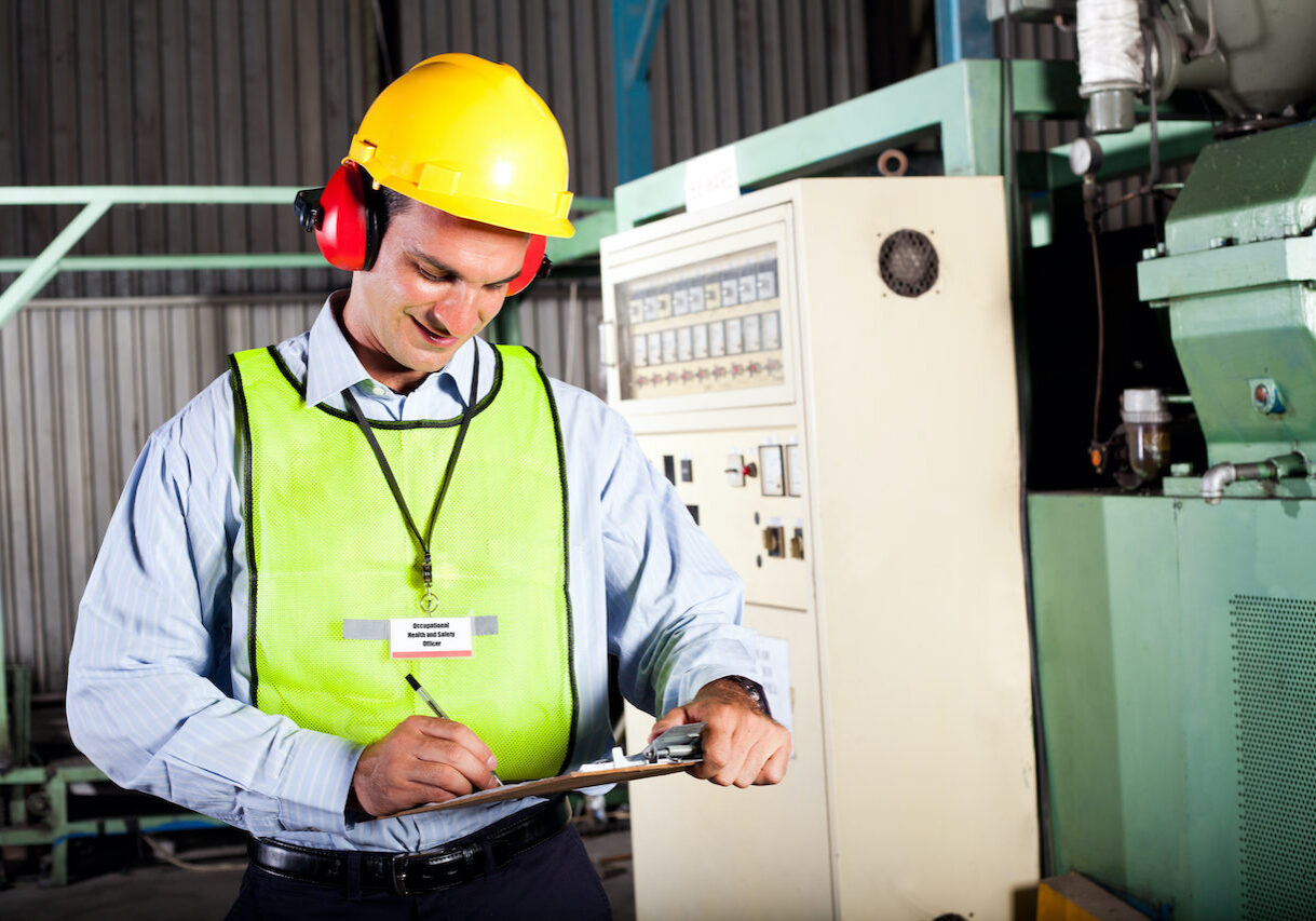 male occupational health and safety officer inside factory doing inspection