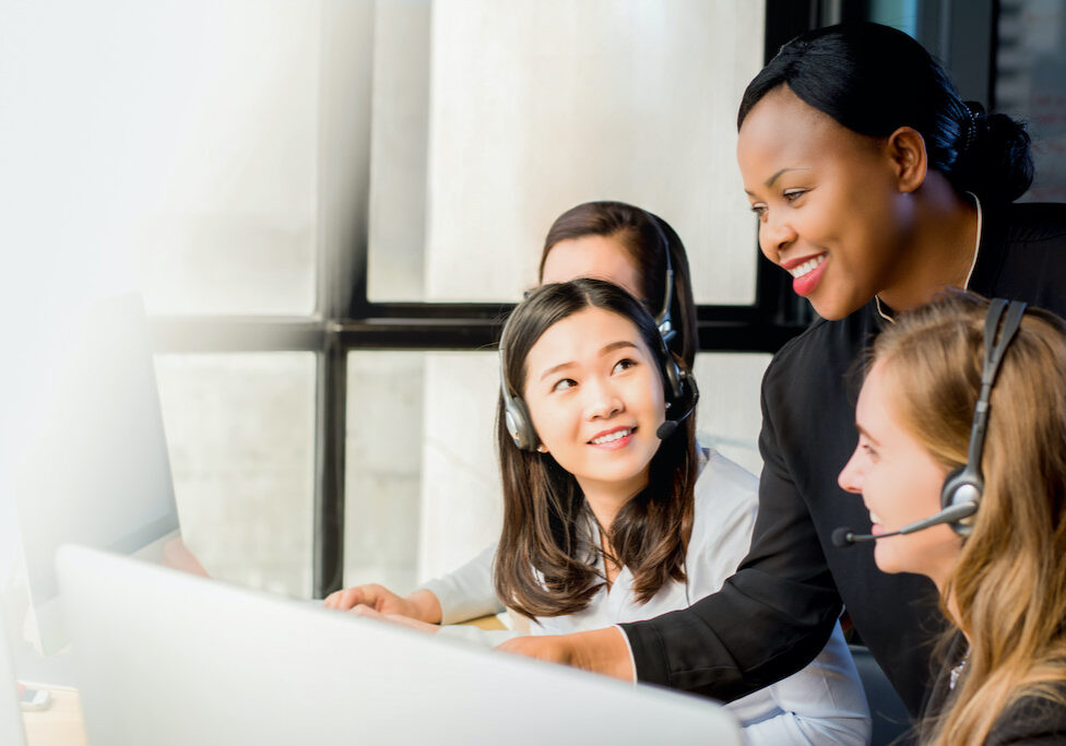 Friendly black businesswoman supervisor training work to her multiethnic colleagues in call center office